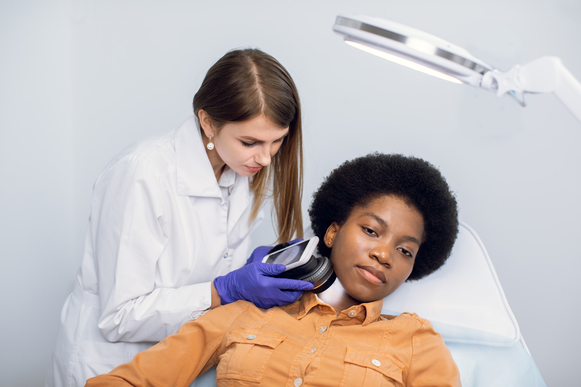 young-african-american-woman-client-lying-on-the-couch-in-modern-dermatology-clinic-having-face.jpg